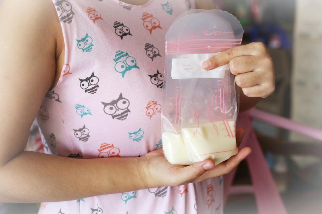 Breastfeeding parent holding three bags of appropriate amounts of human milk (about 4 ounces per bag)