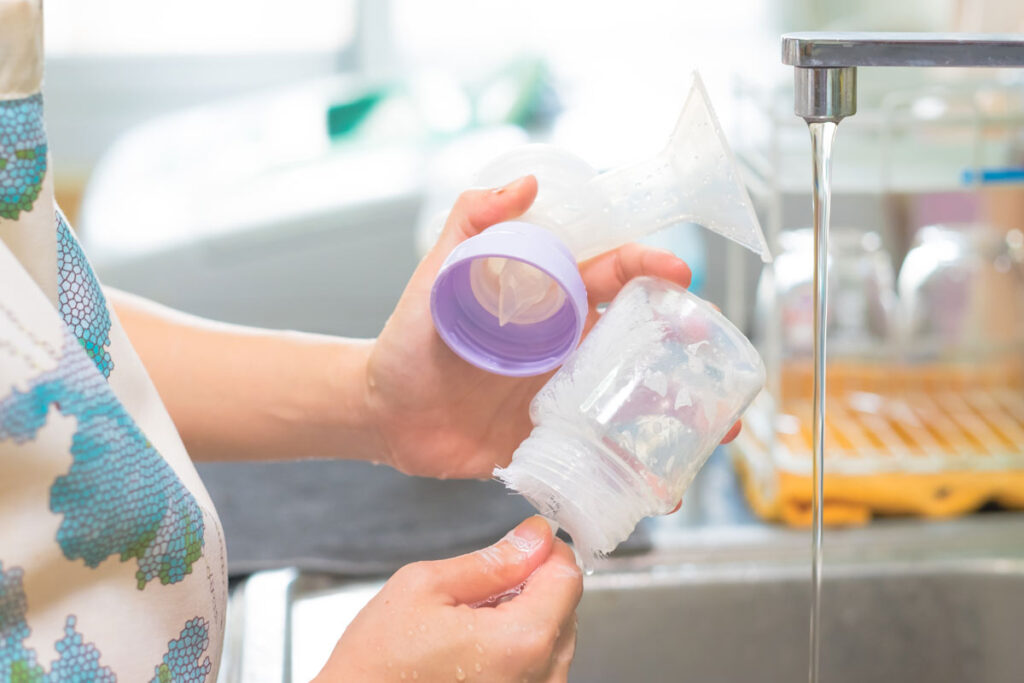 Breastfeeding parent washing bottles and pump flanges